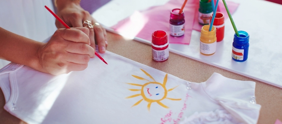 Mujer pintando ropa de bebe